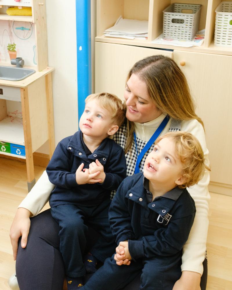 Educadora acompañando a niños en CBS Pre-School